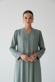 Waist up close-up of Arab model in sage green abaya